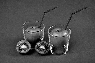 Juice from green apples in a glass with a drinking straw. Monochrome photo.