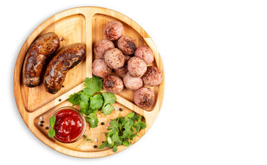 Fried sausages and meat balls with sauce and herbs on a wooden plate. White background. Top.