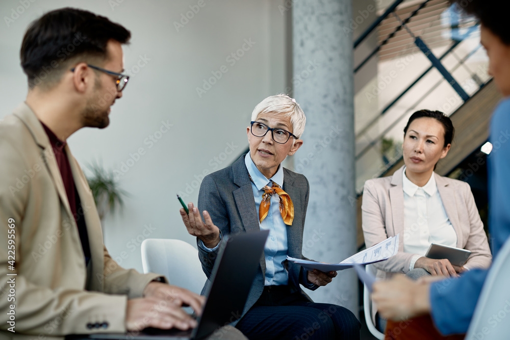 Wall mural Mature executive manager discussing about business data with her team during a briefing in the office.