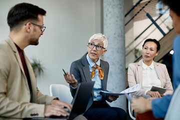 Mature executive manager discussing about business data with her team during a briefing in the...