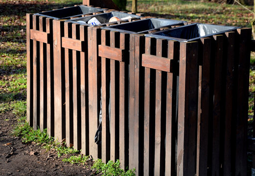 combined waste bin for sorting 4 types of waste. lined with brown wood to better fit the nature park. In the school yard, children learn to sort waste and protect nature