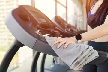Healthy people wiping sweat and cleaning the treadmill with alcohol for a hygiene prevent Corona...