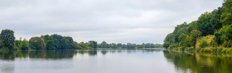 Forest on the river in early autumn, panorama