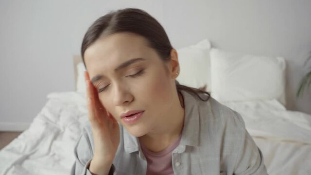 upset young woman with closed eyes suffering from headache