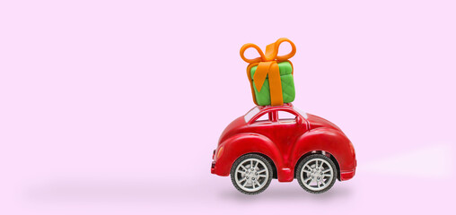 Car with gift box on a roof with on pink background.