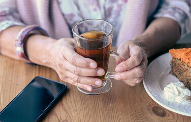 Close-up on woman's hand in coffee shop, enjoying a cup of tea and a carrot cake