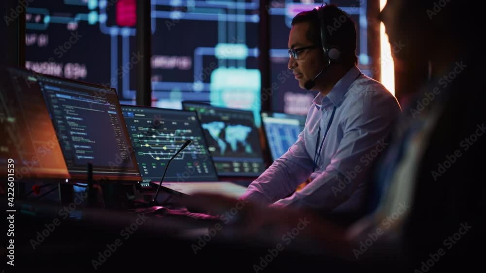 Aufkleber Professional IT Technical Support Specialist and Software Developer Working on Computer in Monitoring Control Room with Digital Screens. Employee Puts on Headphones with Mic and Talking on a Call.