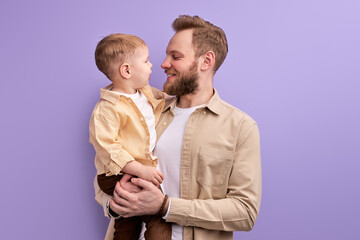 adorable son boy and young father have fun, enjoying time together, isolated on purple