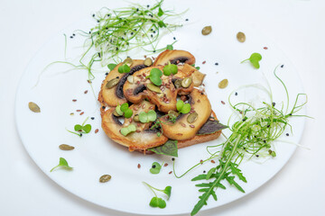 Sandwich with fried mushrooms, basil, pumpkin seeds and microgreens - radish and onion sprouts, served on white plate