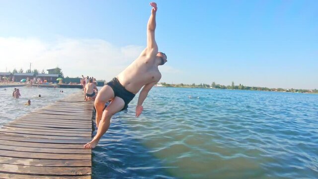 man jumping from wooden dock. somersault