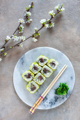 Japanese sushi served with spring cherry tree blossoming branches. Top view, close up on light background.