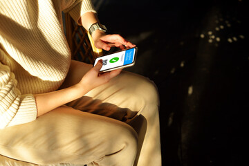 Smartphone displaying a valid digital vaccination certificate passport for COVID-19 in womens hand with hard shadows. Vaccination, disease immunity passport, health and safty travel concepts