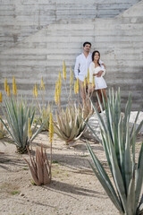 Couple dressed in white standing next to grey wall in tropics