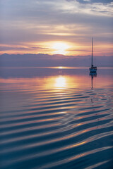 Fototapeta na wymiar Moored sailboat in the bay and sunrise