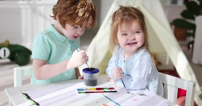 cute kids envolved in drawing activity with watercolor paints at cozy nursery room at home