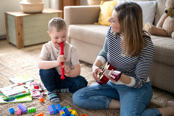 Single mother with down syndrome child at home, playing musical instruments.
