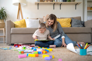 Single mother with down syndrome child at home, reading book.