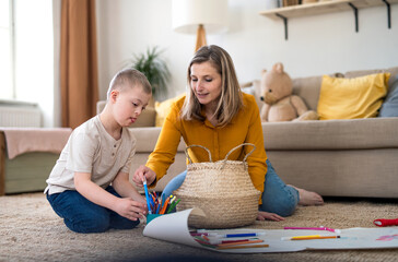 Single mother with down syndrome son at home, drawing pictures.