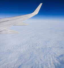 Fototapeta premium Flight restrictions due to Covid 19. View of airplane wing from cabin window, high above the cloudy sky. Traveling on airplane.