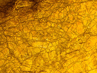 Gold texture rough leaf foil with cracks background. Shiny yellow abstract textured golden stone. Gradient