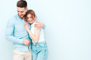 Fototapeta premium Smiling beautiful woman and her handsome boyfriend. Happy cheerful family having tender moments near light blue wall in studio.Pure cheerful models hugging.Embracing each other