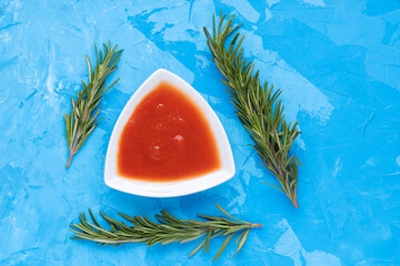 Tomato sauce in white bowl on blue cement background