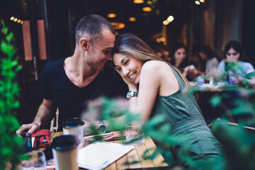Concept of tenderness warm feelings and love in air, carefree Asian woman and happy Caucasan male enjoying positive date in sidewalk cafe flirting during leisure daytime for bonding and cuddling