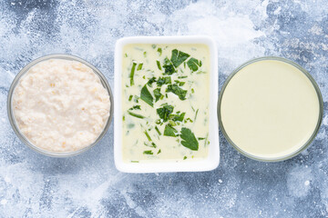 Three condiment bowls with mayonnaise on blue background