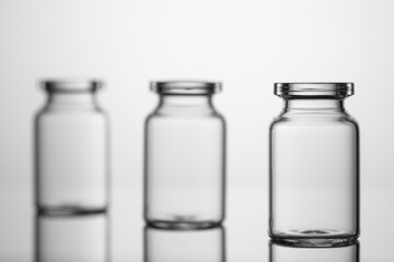 Medicine glass jars, capacity for liquid medicines with an open neck without stopper. Close up shot on a gray background