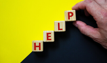Support and help symbol. Wooden cubes with the word 'help'. Businessman hand. Business, psychology, support and help concept. Beautiful yellow and black background, copy space.