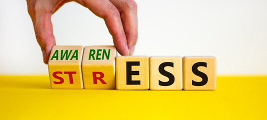 Stress awareness symbol. Businessman turns cubes and changes the word 'stress' to 'awareness'....