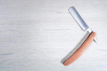 Classic straight razor on a bleached wood background.