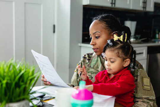 Focused military woman working from home at laptop and paying bills