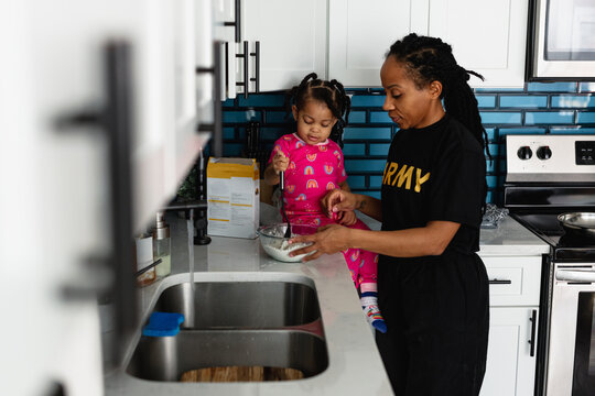 Black army mother cooks breakfast in kitchen with daughter