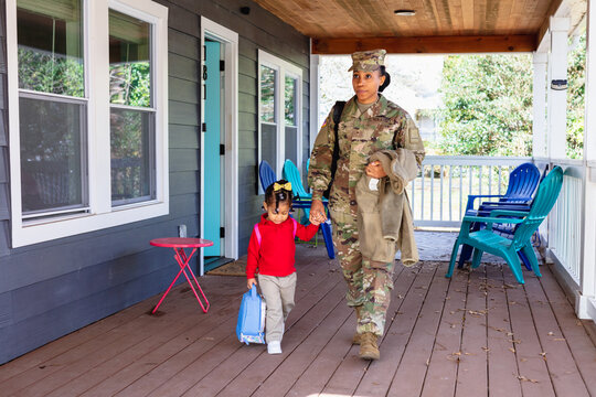 Black woman walking child to school, military personnel