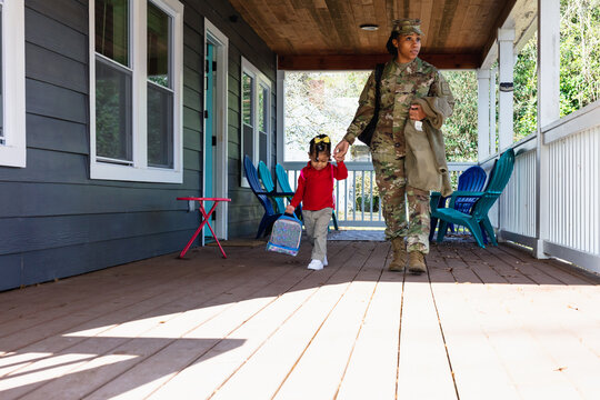 Black woman walking child to school, military personnel