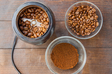 Coffee beans in the mill and grounded coffe in the bowl on the dark background