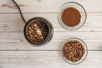 Coffee beans in the mill and grounded coffe in the bowl on the wooden background