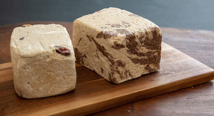 Halva almond nuts and cocoa pieces on wooden table background