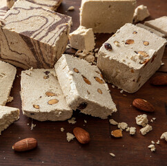 Halva almond nuts and cocoa slices on wooden table background