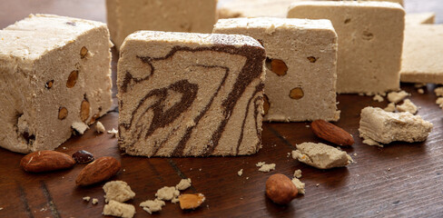 Halva almond nuts and cocoa slices on wooden table background