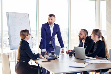 Business people working together in a modern office with cityscape view. The director tells the staff about new technologies. Office work concept