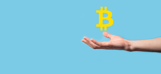 Male hand holding a bitcoin icon on blue background. Bitcoin Cryptocurrency Digital Bit Coin BTC Currency Technology Business Internet Concept.