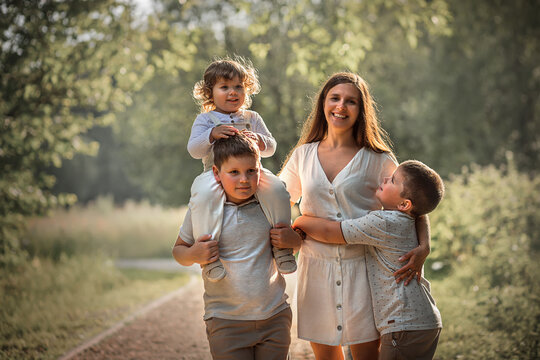 Family portrait with young beautiful mother with her three sons in a park. Image with selective focus and toning