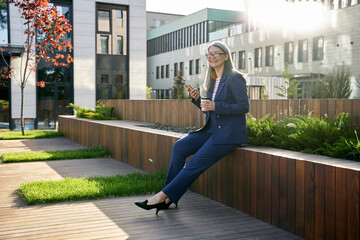 Smiley businesswoman enjoying a cup of coffee and sunshine