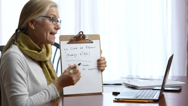 Mature woman remote teacher, coach, tutor, talking giving web teaching spanish language grammar, live webinar making video conference call virtual chat meeting on laptop working from home.