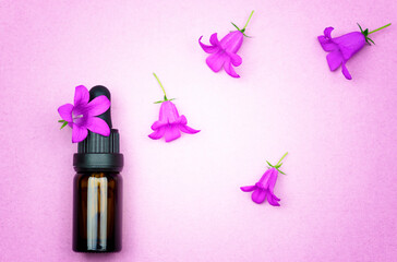 Organic cosmetics. A bottle with oil and flowers on a delicate lilac background.