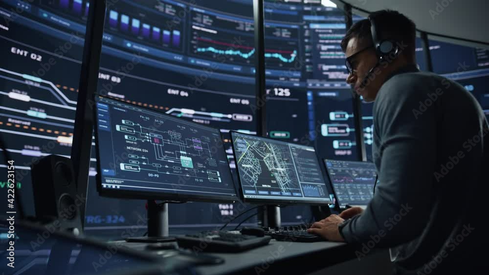 Poster Professional IT Technical Support Specialist and Software Developer Working on Computer in Monitoring Control Room with Digital Screens. Employee Wears Headphones with Mic and Talking on a Call.