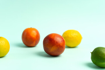 Two ripe red oranges, lime and lemon on a blue background.
