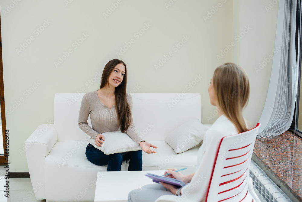 Wall mural A young happy girl communicates with a psychologist in a modern office. Psychological help.